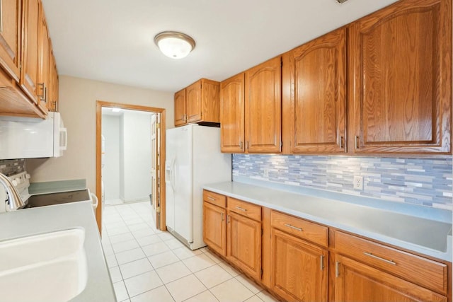 kitchen with backsplash, white appliances, brown cabinetry, light countertops, and light tile patterned floors