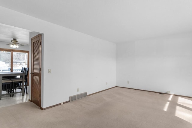 spare room featuring visible vents, light carpet, baseboards, and a ceiling fan