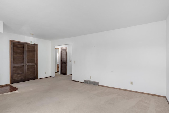 unfurnished bedroom with visible vents, baseboards, and light colored carpet