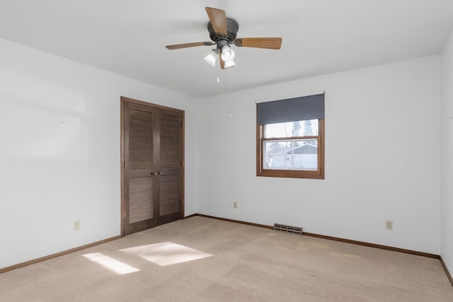 unfurnished bedroom featuring light colored carpet, baseboards, visible vents, and a closet