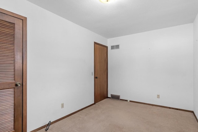 unfurnished bedroom with visible vents, light colored carpet, and baseboards