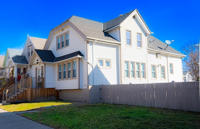 view of property exterior with a lawn, roof with shingles, and fence