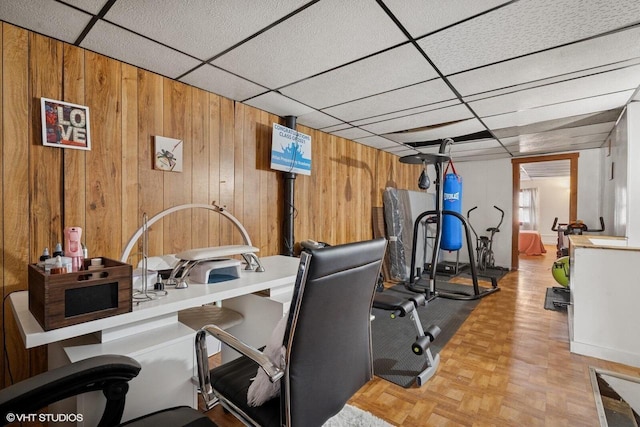 workout area with a drop ceiling and wood walls