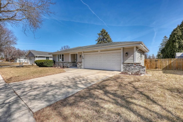 ranch-style home with fence, concrete driveway, a front yard, a garage, and stone siding