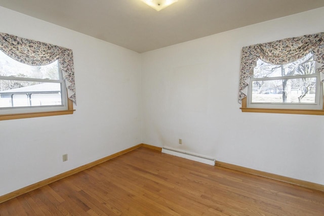 spare room featuring baseboards, baseboard heating, and wood finished floors