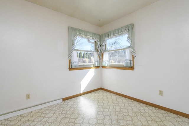 spare room with tile patterned floors, a baseboard heating unit, and baseboards