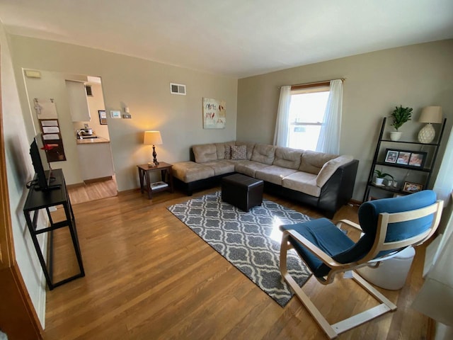 living area featuring visible vents and wood finished floors