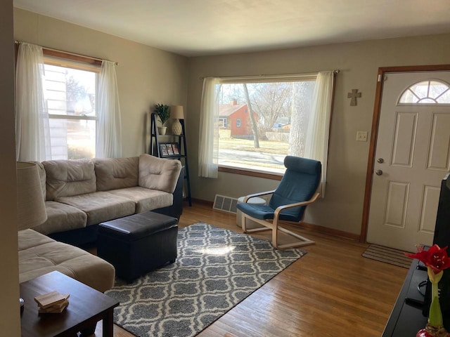 living room featuring visible vents, baseboards, and wood finished floors