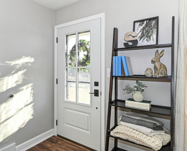 doorway with dark wood-type flooring, baseboards, and visible vents