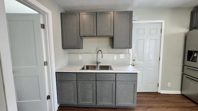 kitchen with light countertops, gray cabinets, dark wood-style flooring, and a sink