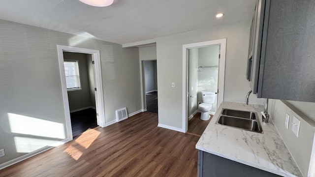 kitchen featuring dark wood-type flooring, baseboards, visible vents, and a sink