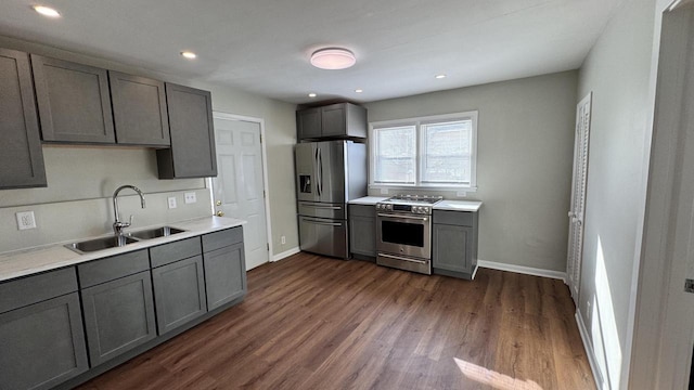 kitchen featuring gray cabinets, a sink, dark wood-style floors, stainless steel appliances, and baseboards