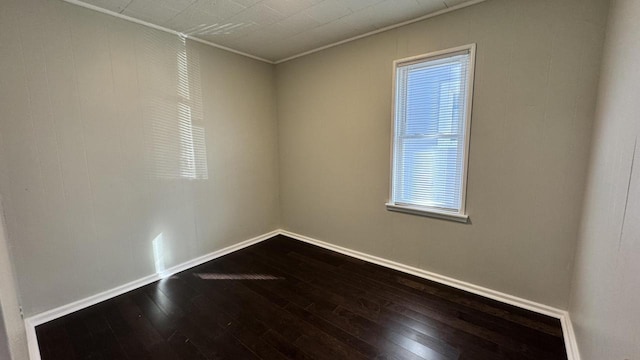 spare room featuring dark wood-type flooring and baseboards