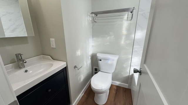 bathroom with toilet, vanity, baseboards, and wood finished floors