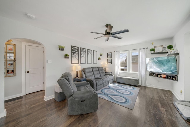 living area featuring baseboards, wood finished floors, arched walkways, and ceiling fan