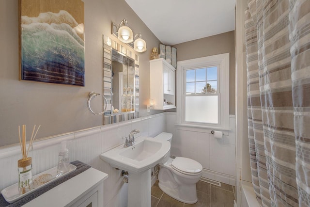 bathroom featuring a wainscoted wall, visible vents, toilet, a shower with shower curtain, and tile patterned flooring