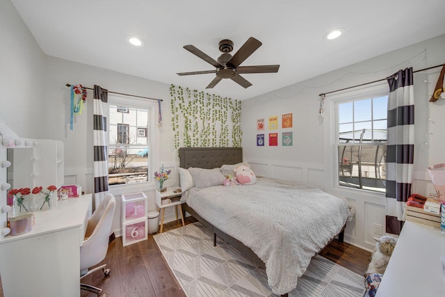 bedroom with wainscoting, multiple windows, and dark wood-type flooring