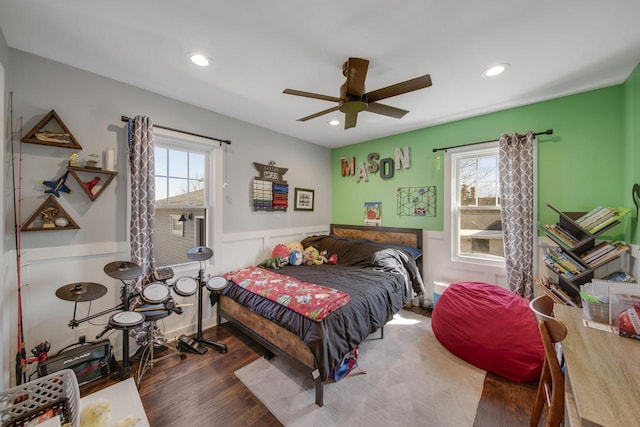 bedroom with multiple windows, wood finished floors, recessed lighting, and wainscoting