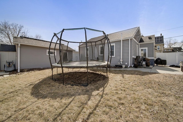 view of property exterior featuring a patio, a trampoline, and fence