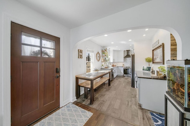 foyer featuring arched walkways, recessed lighting, and light wood-style floors