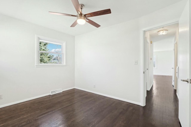 spare room featuring visible vents, baseboards, a ceiling fan, and dark wood-style flooring