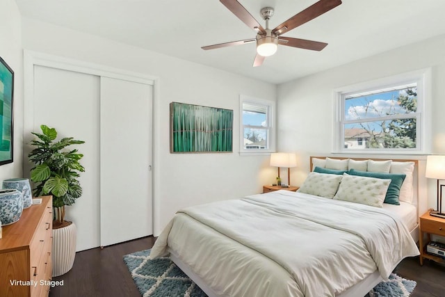 bedroom with a closet, dark wood-type flooring, and ceiling fan