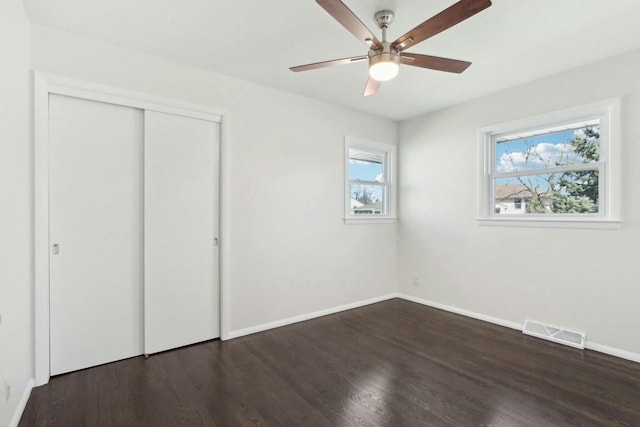 unfurnished bedroom with a closet, visible vents, baseboards, and wood finished floors