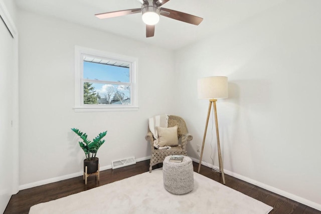 living area with visible vents, baseboards, wood finished floors, and a ceiling fan