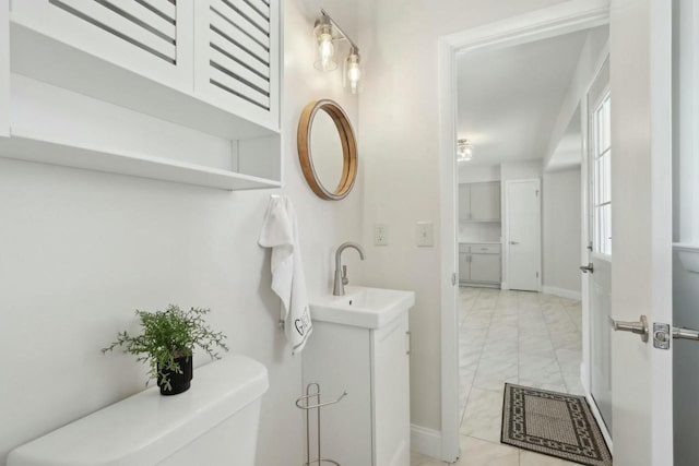 half bathroom with vanity, toilet, baseboards, and marble finish floor