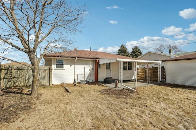 rear view of property featuring an attached carport, entry steps, and fence