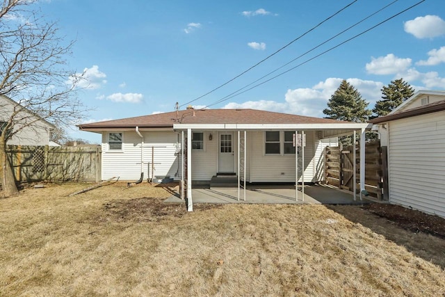 rear view of house featuring fence, entry steps, roof with shingles, a lawn, and a patio area