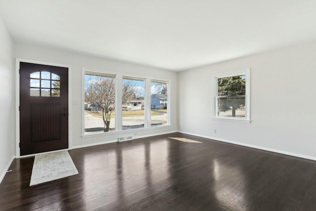 foyer entrance with baseboards, a healthy amount of sunlight, and dark wood-style floors