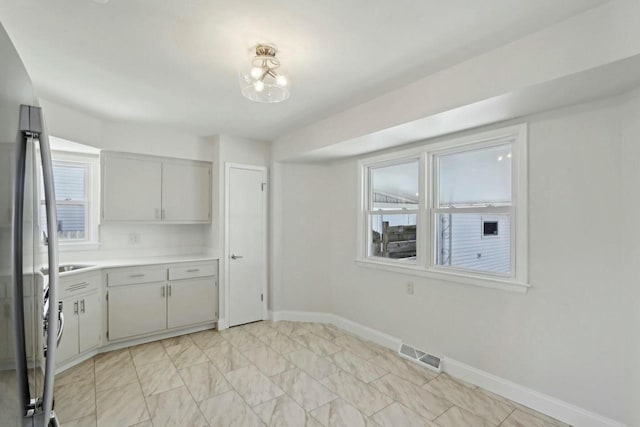 kitchen featuring visible vents, gray cabinets, freestanding refrigerator, light countertops, and baseboards