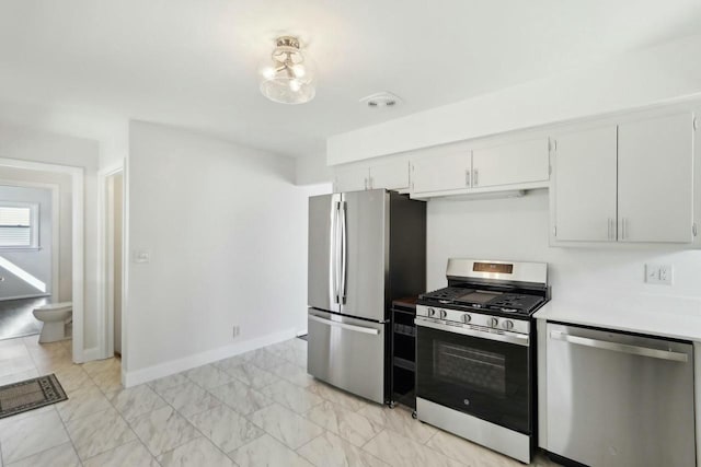 kitchen with baseboards, light countertops, appliances with stainless steel finishes, white cabinets, and marble finish floor