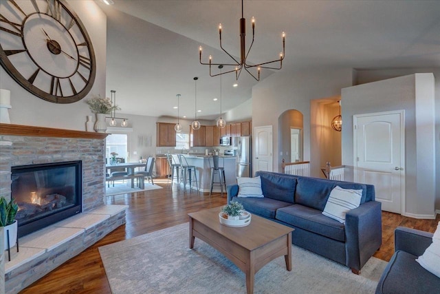 living area with a chandelier, recessed lighting, wood finished floors, arched walkways, and high vaulted ceiling