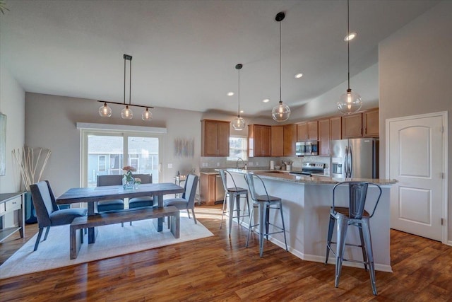 kitchen featuring dark wood-type flooring, appliances with stainless steel finishes, a center island, and brown cabinetry