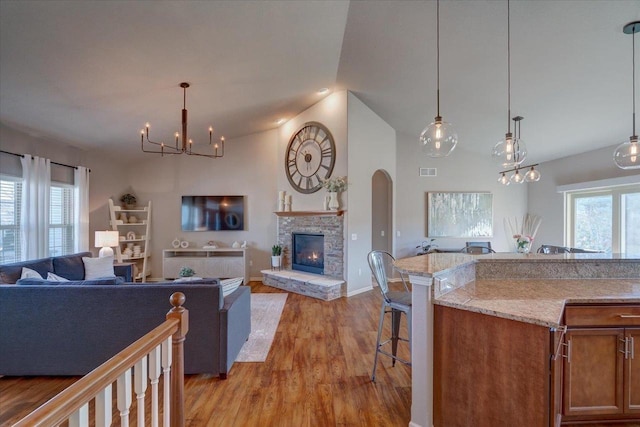 interior space featuring a chandelier, a healthy amount of sunlight, a fireplace, and light wood-style floors