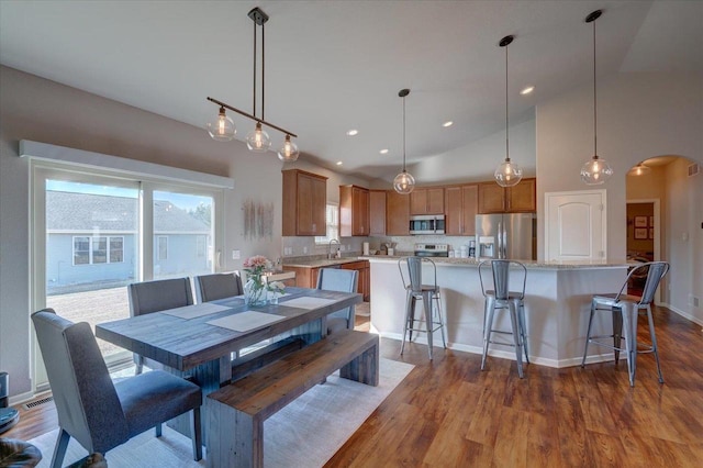 dining area with visible vents, arched walkways, high vaulted ceiling, and dark wood-style floors