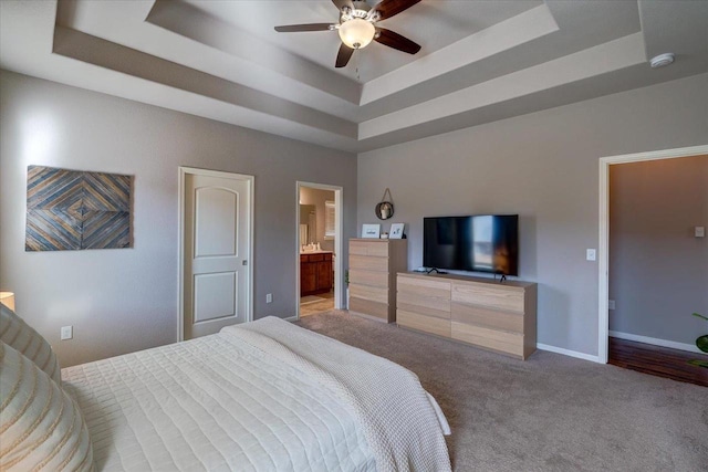 bedroom featuring baseboards, a raised ceiling, carpet floors, and ensuite bath