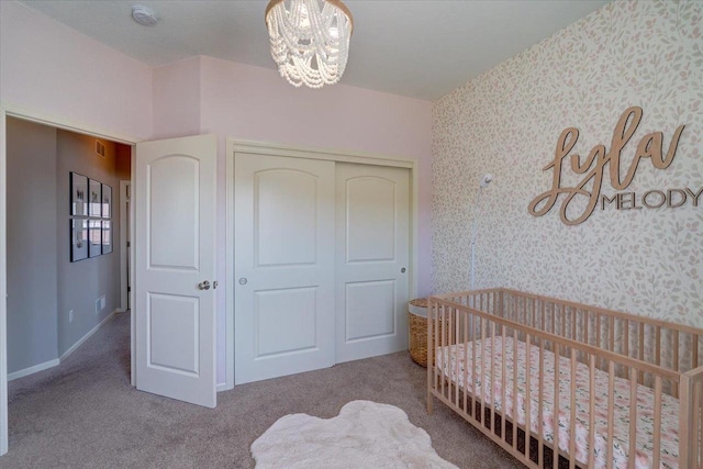 carpeted bedroom with a closet, baseboards, wallpapered walls, and an inviting chandelier