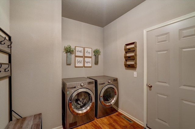 laundry room with visible vents, baseboards, laundry area, wood finished floors, and independent washer and dryer