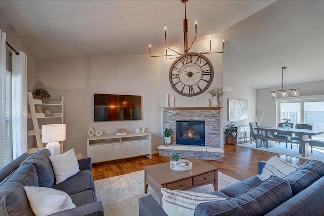 living area with a stone fireplace, wood finished floors, and a towering ceiling