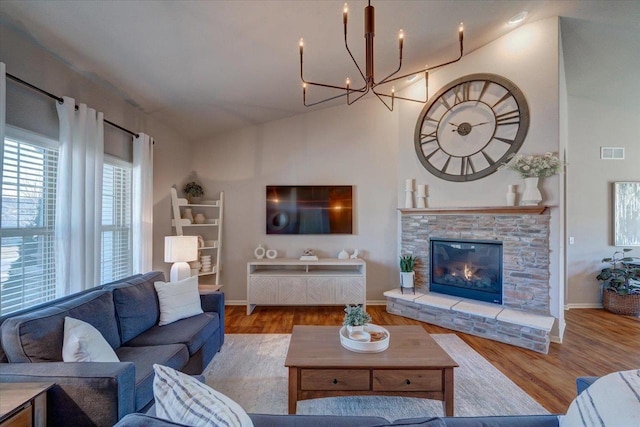 living room with vaulted ceiling, a notable chandelier, wood finished floors, and visible vents