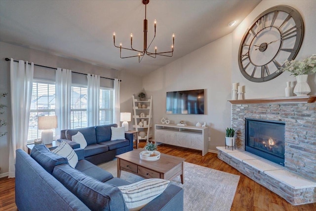 living room with a stone fireplace, an inviting chandelier, wood finished floors, and baseboards