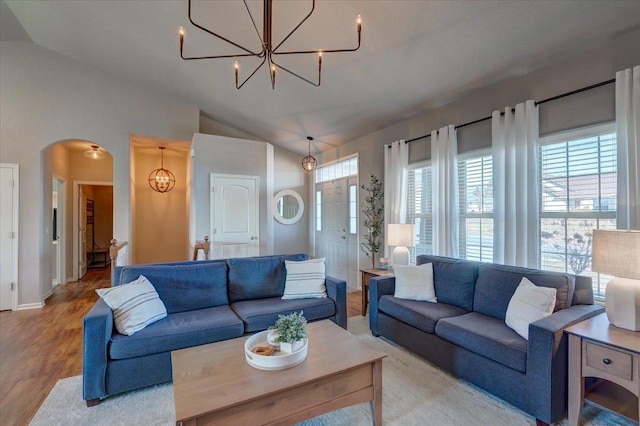 living room featuring arched walkways, a notable chandelier, and a healthy amount of sunlight