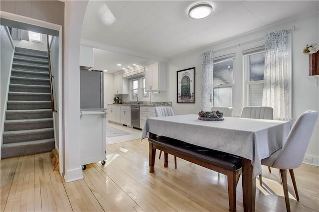 dining area featuring light wood-type flooring and stairway