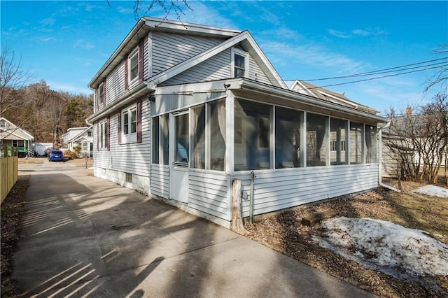 view of side of home with driveway and a sunroom