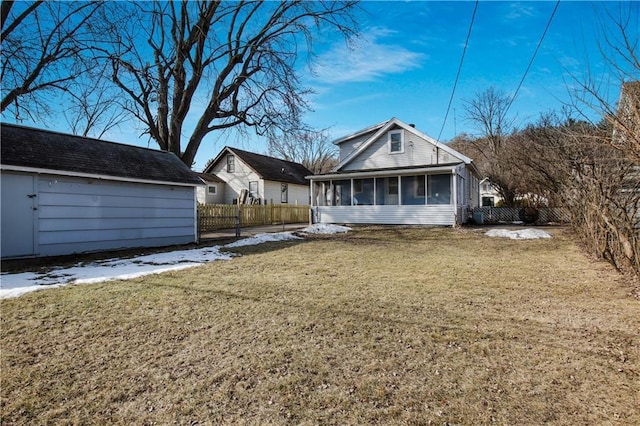 rear view of property featuring a lawn, fence, and a sunroom