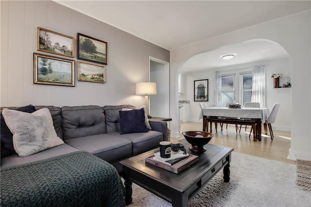 living room with wood finished floors, arched walkways, and baseboards