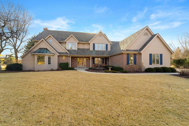 view of front of house with brick siding, french doors, a shingled roof, and a front lawn